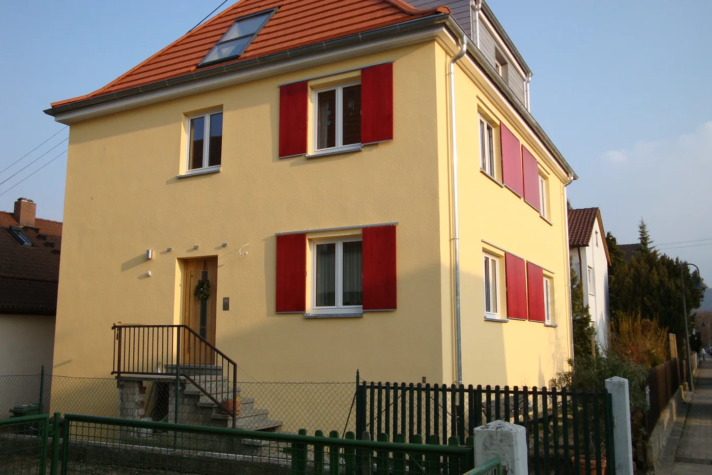 Sanierte Hausfassade mit neuem Außenputz und Farbgestaltung, fertiges Projekt